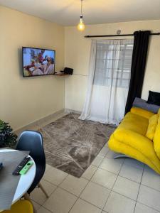 a living room with a yellow couch next to a window at Ample Residence in Nairobi