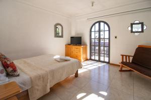 Suites Sevilla في بوبلا: غرفة نوم بسرير وتلفزيون وأريكة