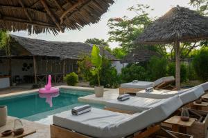 a pool with two lounge chairs and an umbrella at Kendwa Breeze Bungalows in Kendwa