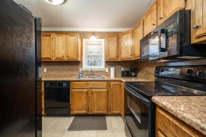 eine Küche mit Holzschränken und einem schwarzen Kühlschrank in der Unterkunft Idas Ideal Homestead cozy 3Bed1Bath perfect for Work-Stay or Family Vacay in Morrilton