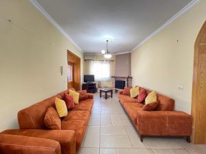 a living room with brown leather couches and a television at Tirana Center 2Bedrooms in Tirana
