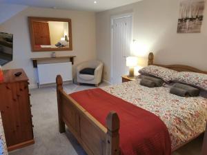 a bedroom with a bed and a chair and a mirror at Cosy Cottage in a quaint village in North Devon. in Bideford