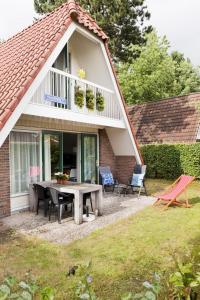 a patio with a table and chairs in front of a house at Holiday Home Ruiten AA comfort by Interhome in Vlagtwedde