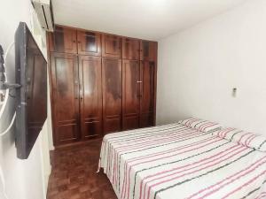 a bedroom with a bed and wooden cabinets at Espaçoso em excelente localização na Barra in Salvador