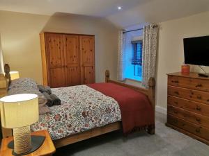 a bedroom with a bed and a dresser and a television at Cosy Cottage in a quaint village in North Devon. in Bideford