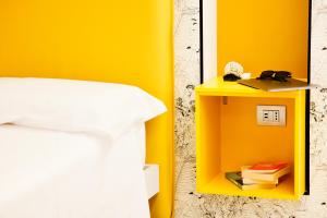 a yellow side table next to a bed and a mirror at Casa dei Venti - Guest House in Terracina