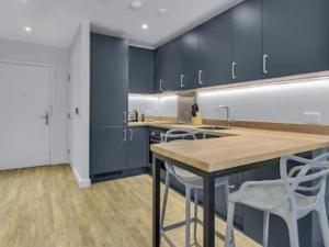 a kitchen with blue cabinets and a table and chairs at Apartment Wembley Park apartments-1 by Interhome in London