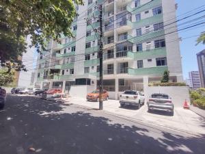 a street with cars parked in front of a tall building at Espaçoso em excelente localização na Barra in Salvador
