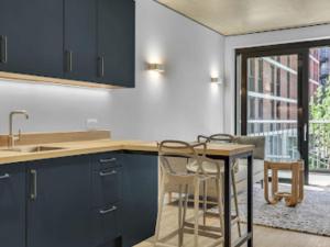 a kitchen with blue cabinets and a table and chairs at Apartment Wembley Park apartments-1 by Interhome in London