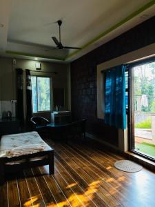 a bedroom with a wooden floor and a ceiling fan at Sana Riverside in Madikeri