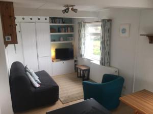 a living room with a couch and a television at Cosy Cornish cottage with rural views in Newquay
