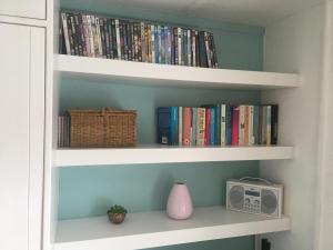 un estante de libros lleno de libros y una radio en Cosy Cornish cottage with rural views, en Newquay