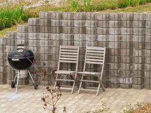 two chairs and a grill next to a wall at Holiday Home Edo - 575m from the sea in Funen by Interhome in Spodsbjerg