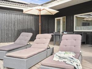 two chairs and a table with an umbrella on a deck at Holiday Home Edo - 575m from the sea in Funen by Interhome in Spodsbjerg