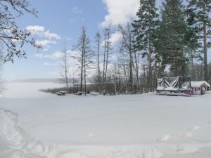 um campo coberto de neve com uma casa e árvores em Holiday Home Villa lagerlöf by Interhome em Vääksy