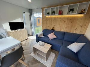 a living room with a blue couch and a tv at Holiday Home Tiny Haus Anellie by Interhome in Riedenburg