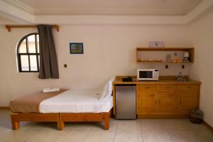 - une petite chambre avec un lit et un four micro-ondes dans l'établissement Suites Sevilla, à Puebla