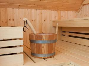 a wooden tub in a sauna with a broom in it at Holiday Home Heerd Wellness de Luxe by Interhome in Vlagtwedde