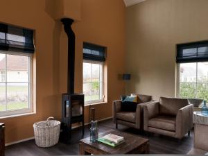 a living room with a fireplace and a couch and chairs at Holiday Home Heerd Wellness de Luxe by Interhome in Vlagtwedde