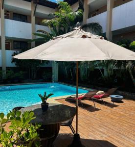 a tan umbrella sitting next to a swimming pool at Recanto da Orla in Aracaju