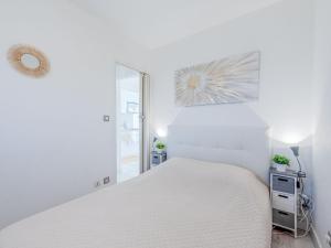 ein weißes Schlafzimmer mit einem weißen Bett und einem Spiegel in der Unterkunft Apartment Grand Bleu by Interhome in Le Barcarès