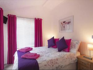 a bedroom with a bed with pink and purple pillows at Chalet Windermere Lodge by Interhome in Windermere