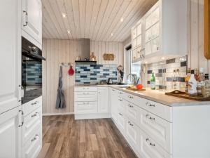 a kitchen with white cabinets and wooden floors at Holiday Home Gyrid - 150m from the sea in Djursland and Mols by Interhome in Rønde