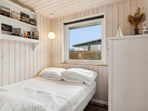 a small bedroom with a bed and a window at Holiday Home Gyrid - 150m from the sea in Djursland and Mols by Interhome in Rønde