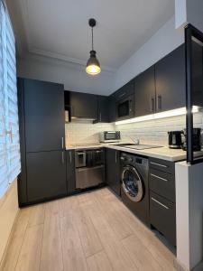 a kitchen with black cabinets and a washer and dryer at L'écrin Saint Mandé in Saint-Mandé