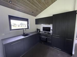 a kitchen with black cabinets and a window at Holiday Home De Parel by Interhome in Scherpenisse