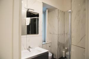 La salle de bains blanche est pourvue d'un lavabo et d'une douche. dans l'établissement Residence Black & White, à Naples