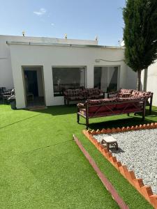 a house with two benches in a yard at شاليه قلب الهدا 3-4 in Al Hada