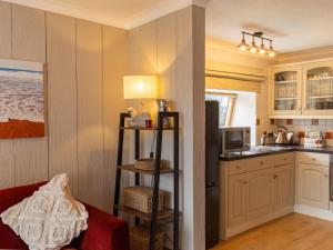 a kitchen with a living room with a red couch at Holiday Home Stable Cottage by Interhome in Drumnadrochit