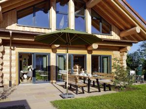 a patio with a table and a green umbrella at Chalet Schwarzwaldchalet de luxe mit Sauna by Interhome in Heitersheim