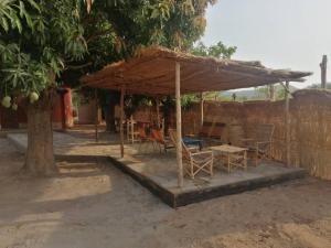 un patio con mesa y sillas bajo una sombrilla en Le Jardin de L'Atacora, en Natitingou