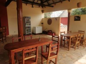 a dining room with two wooden tables and chairs at Le Jardin de L'Atacora in Natitingou