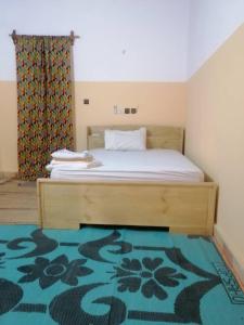 a bedroom with a bed with a green rug at Le Jardin de L'Atacora in Natitingou