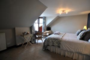 a bedroom with a bed and a desk with a chair at Kittiwake House- charming coastal home in Saint Monance