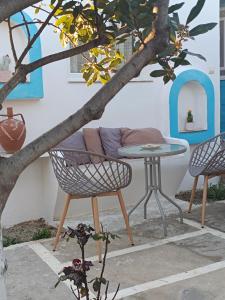 un patio con 2 sillas, una mesa y un árbol en PERIVOLI 1-CHORA(5min away from the center by car), en Agkidia