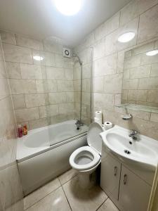 a bathroom with a toilet and a tub and a sink at Fernando flats in London