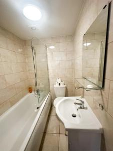 La salle de bains est pourvue d'un lavabo, d'une baignoire et de toilettes. dans l'établissement Fernando flats, à Londres