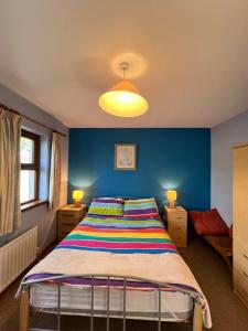 a bedroom with a bed with a blue wall at Beautiful Lakeside Holiday Home (6 Portinode Cottages) in Enniskillen