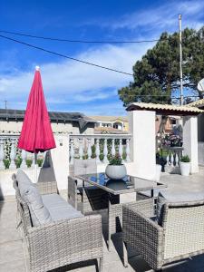 patio ze stołem, krzesłami i różowym parasolem w obiekcie The Port House Sea Breeze w mieście Agios Georgios
