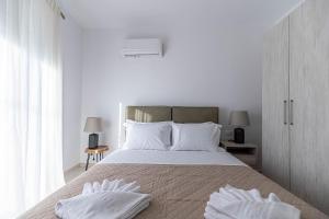 a white bedroom with a large bed with white pillows at Archangelos SKY Junior Apartment in Archangelos