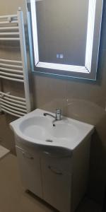 Baño con lavabo blanco bajo una ventana en Apartament 2 camere Ultracentral, en Tîrnăveni