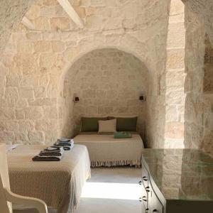 - une chambre avec 2 lits dans un mur en pierre dans l'établissement Trullanto, à Francavilla Fontana