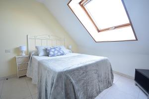 a white bedroom with a bed with a skylight at Apartamento con terraza frente al mar en O Grove in O Grove