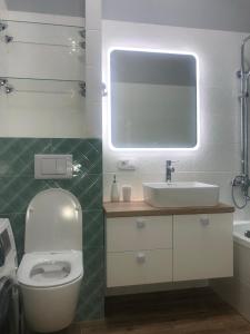 uma casa de banho com um WC, um lavatório e um espelho. em ЖК Новый Степной em Karaganda