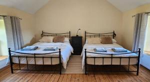 two twin beds in a bedroom with two windows at The Home House in Plumb Bridge