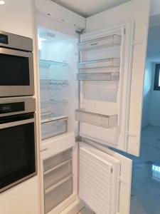 a white refrigerator with its door open in a kitchen at Superbe appartement JO 2024 in Plaisir